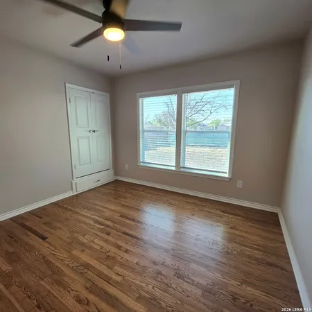 a view of an empty room with window and wooden floor