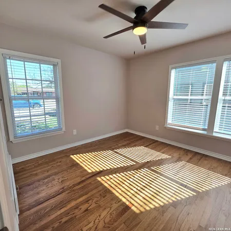 a view of an empty room with window and a chandelier fan