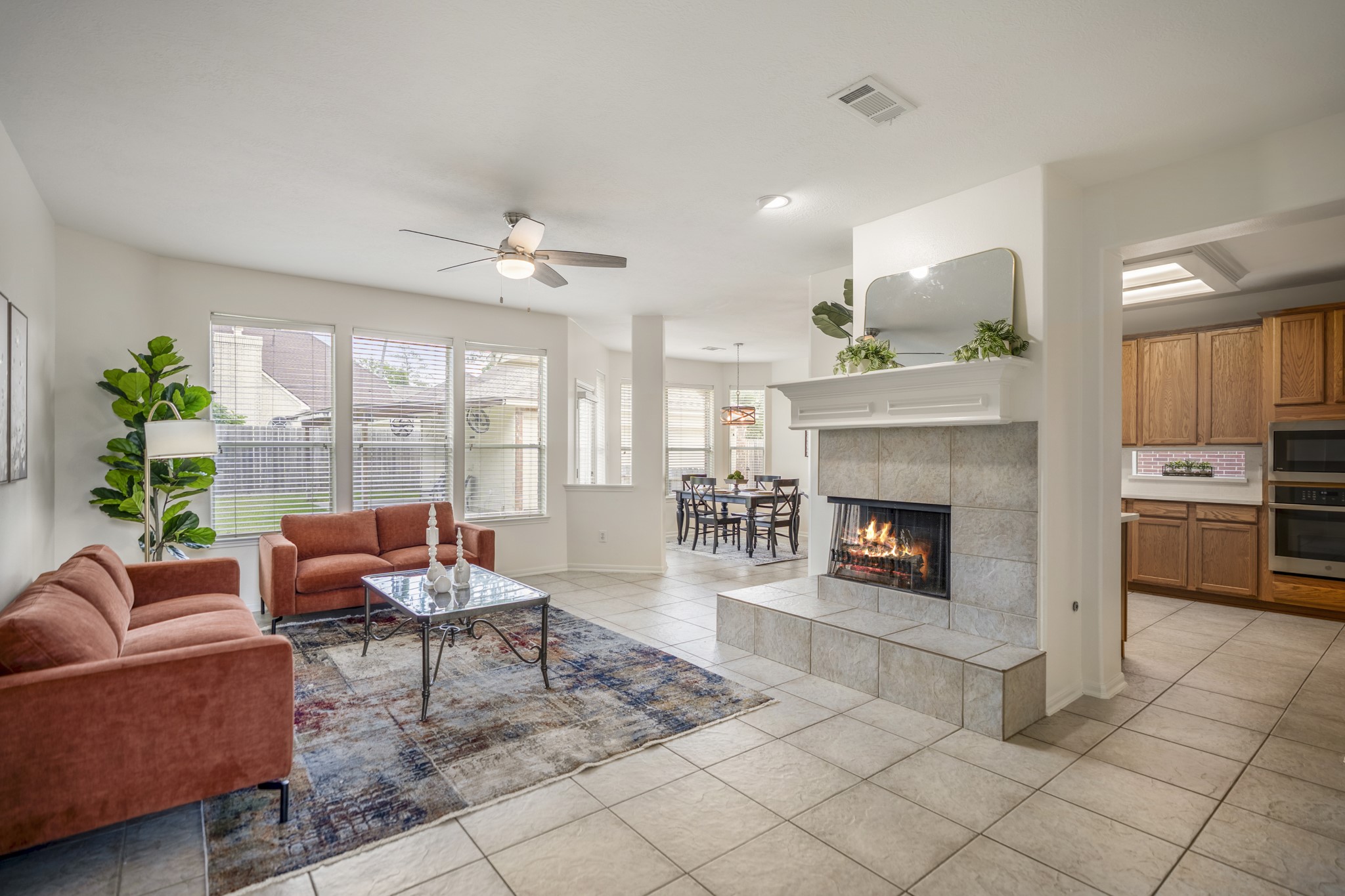 19106 South Rim Trail Spring, TX 77388 - Photo 17 of 50 From this angle of the living room, the main level opens into the everyday gathering space, with the kitchen to the right and the breakfast area just beyond the fireplace. Large backyard-facing windows bring in natural light, while the tile surround and raised hearth add a cozy focal point for evenings at home. The way these spaces connect makes daily life feel easy — cooking in the kitchen, casual meals nearby, and room to relax all within view of one another.