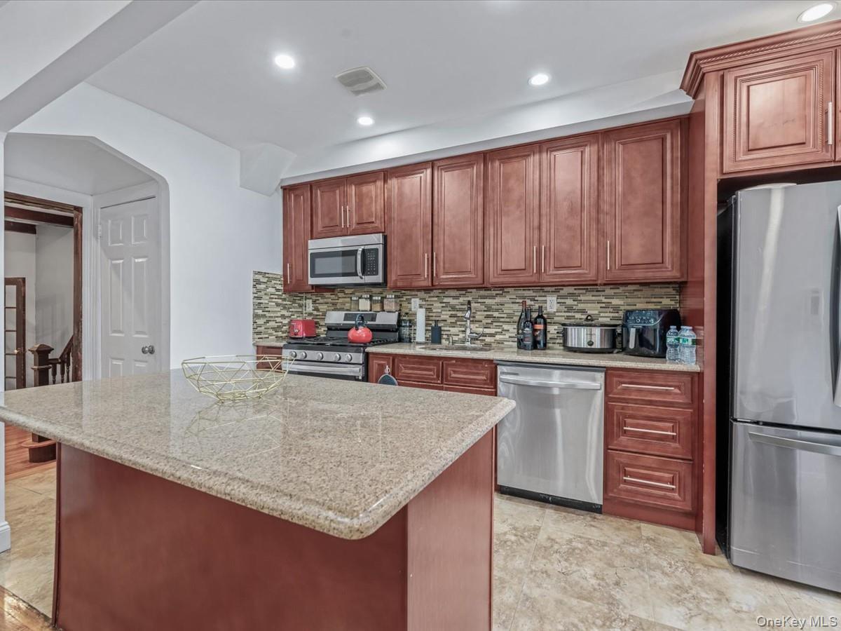 172-09 Sayres Avenue Queens, NY 11433 - Photo 8 of 23 a kitchen with kitchen island granite countertop wooden cabinets a refrigerator and a sink with wooden floors