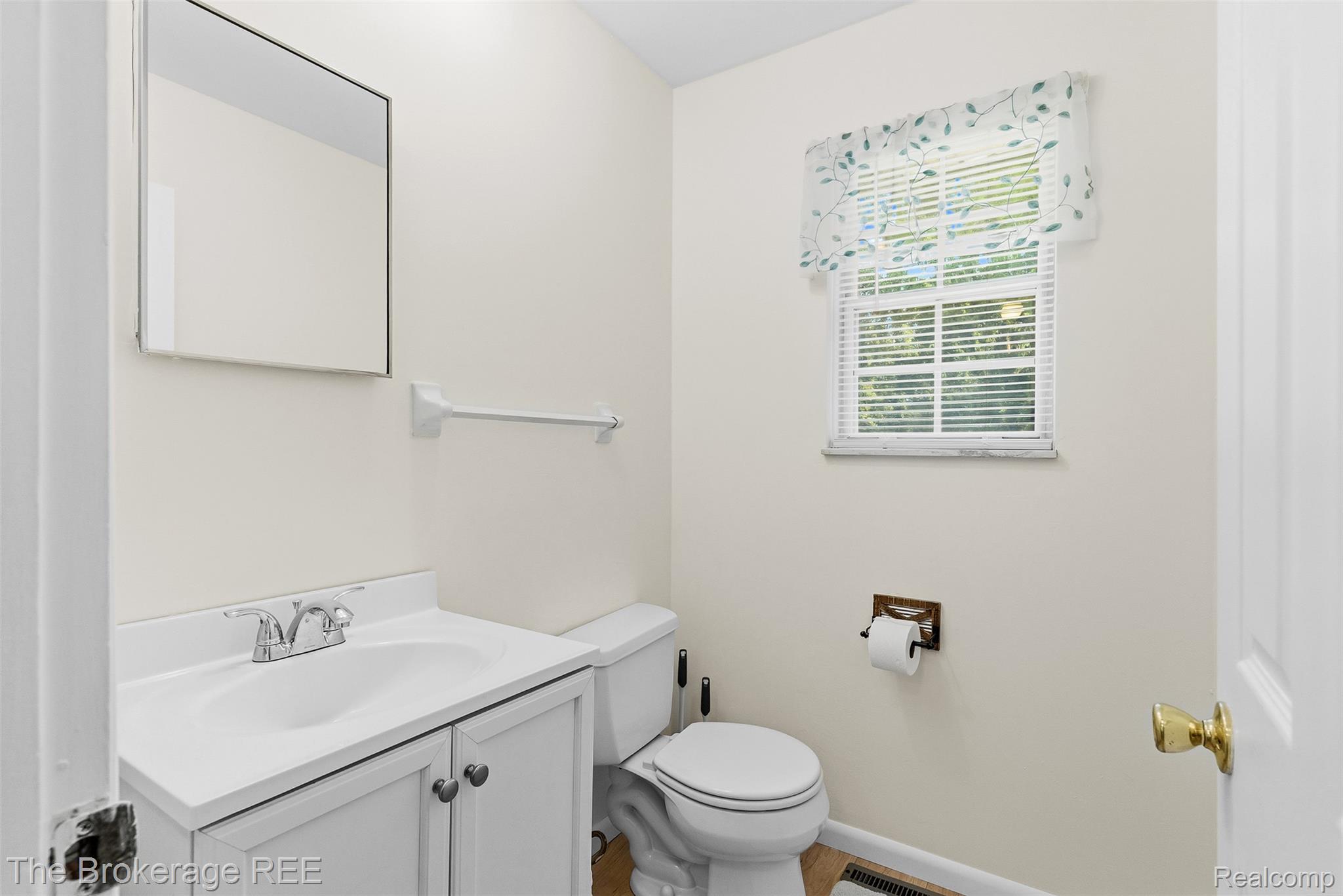 6509 Silver Lake Road Linden, MI 48451 - Photo 23 of 43 Bathroom featuring a white vanity with integrated sink, chrome faucet, wall-mounted mirror, and a window with horizontal blinds