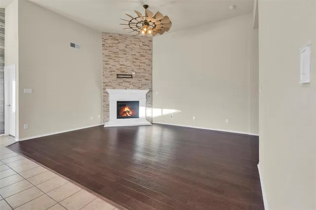an empty room with wooden floor fireplace and chandelier fans
