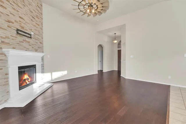a view of an empty room with wooden floor and a fireplace
