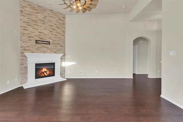 a view of an empty room with wooden floor fireplace and a window
