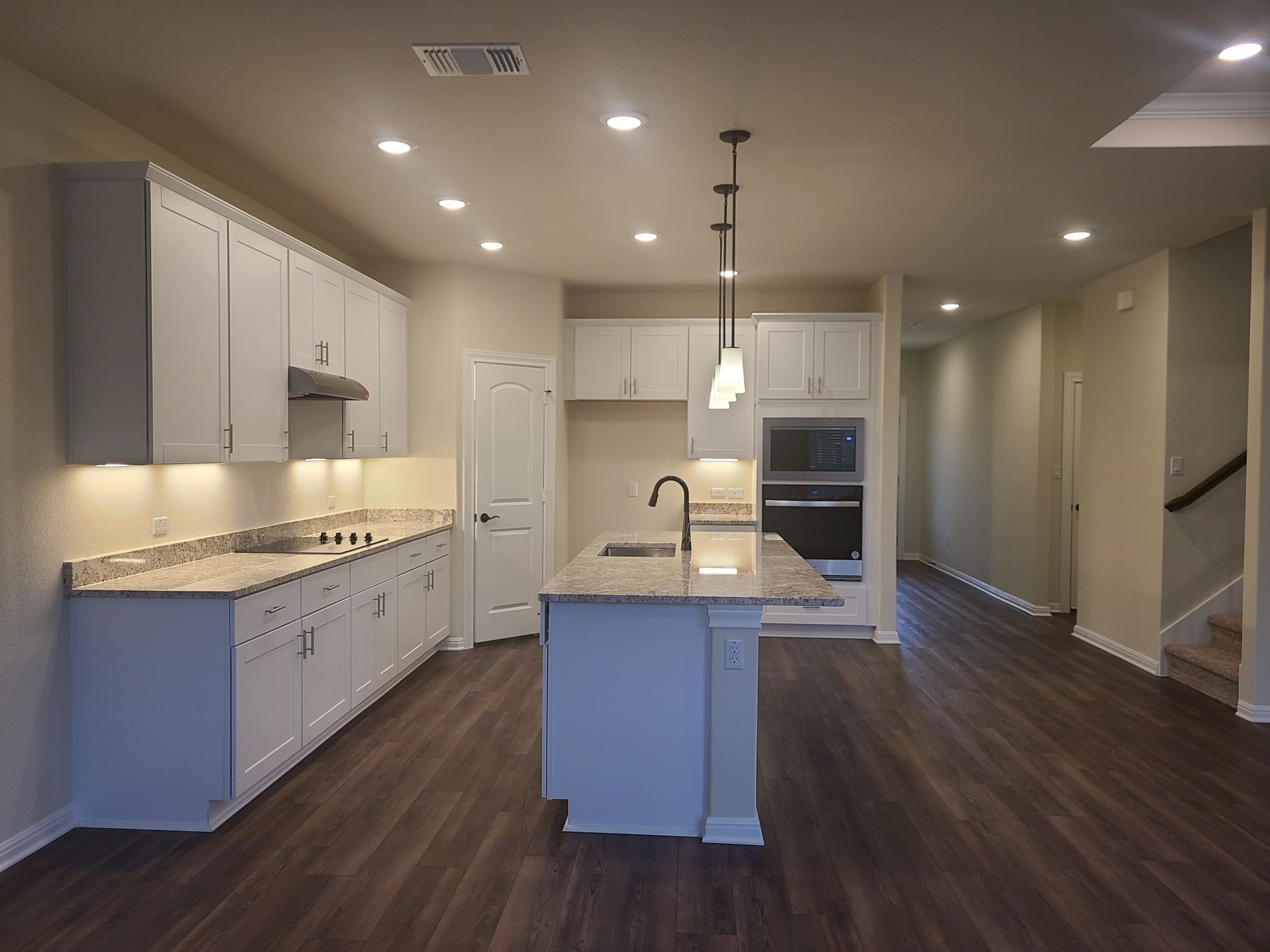 32 Pacific Loon Street Leander, TX 78641 - Photo 4 of 34 a kitchen with kitchen island granite countertop wooden floors wooden cabinets and stainless steel appliances