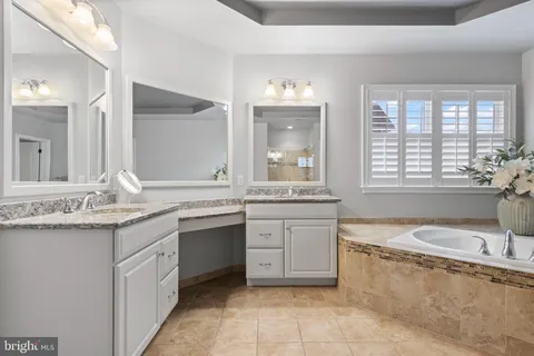 a bathroom with a granite countertop bathtub a sink and a window