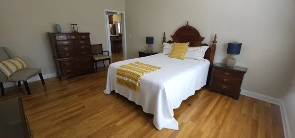 a bedroom with a bed a dresser and wooden floor
