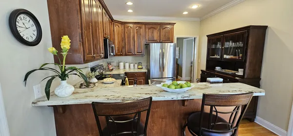 a view of kitchen island with granite countertop a sink a stove and a dining table