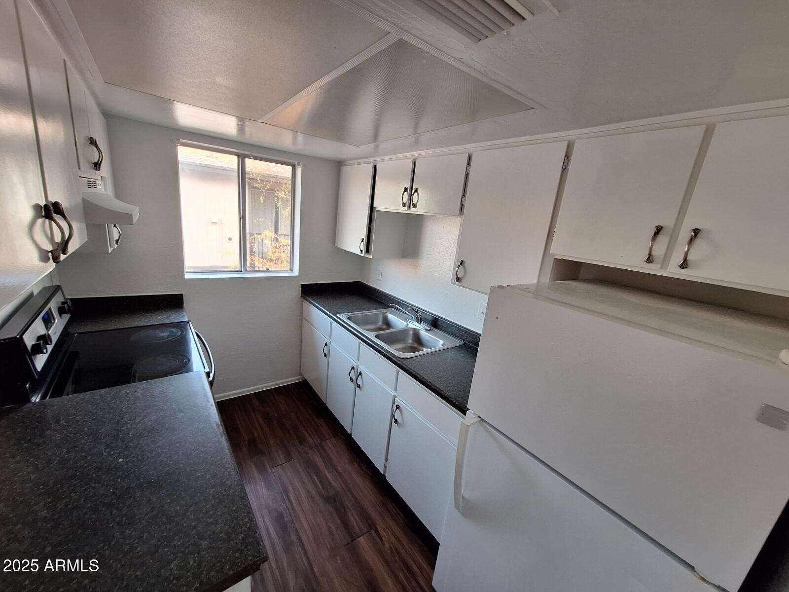 2029 North Hunt Circle, Unit 202 Mesa, AZ 85203 - Photo 5 of 9 a kitchen with granite countertop white cabinets and white appliances