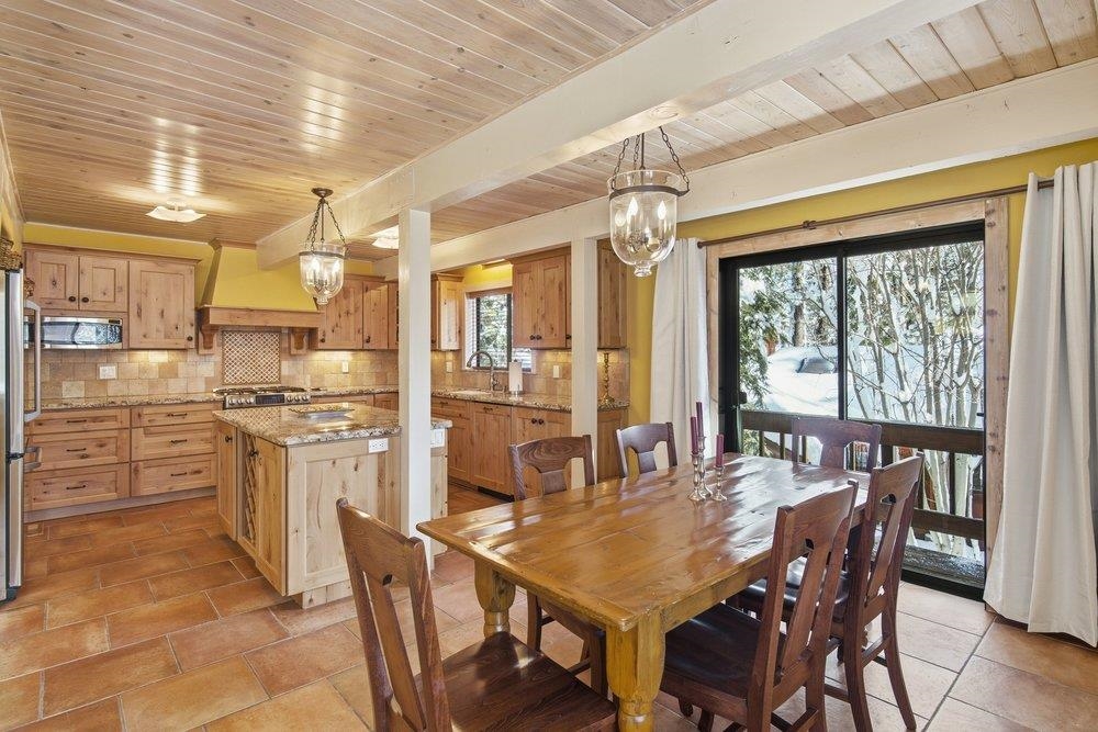 1499 Sandy Way Olympic Valley, CA 96146 - Photo 11 of 28 a kitchen with stainless steel appliances kitchen island granite countertop a table chairs and wooden cabinets