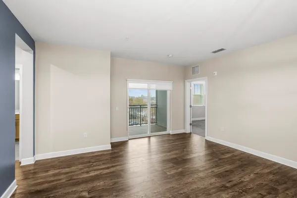 a view of an empty room with wooden floor and a window