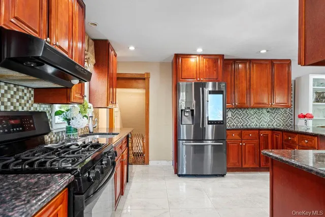 a kitchen with stainless steel appliances granite countertop a stove a refrigerator and a sink