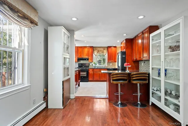 a view of a kitchen with kitchen island wooden floors and stainless steel appliances