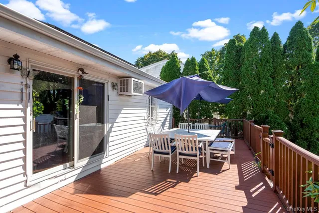 a view of a roof deck with table and chairs under an umbrella with wooden floor and fence