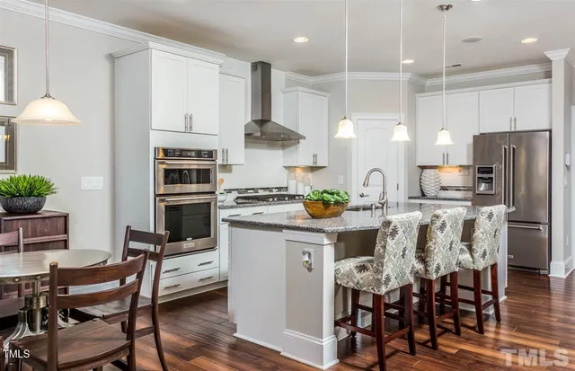 a kitchen with stainless steel appliances a dining table chairs stove and refrigerator