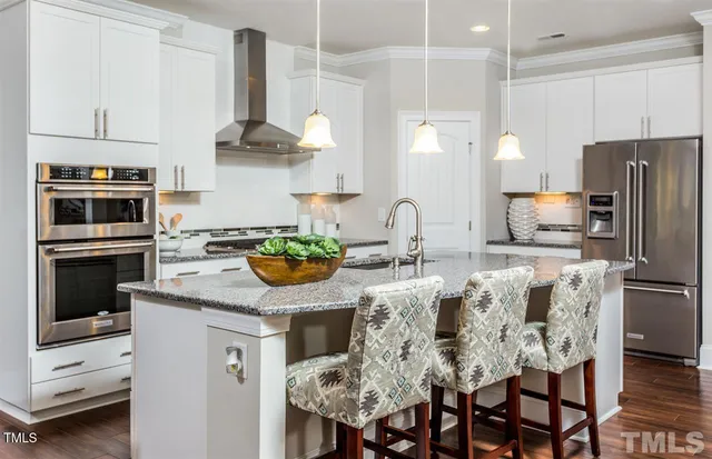 a kitchen with stainless steel appliances kitchen island granite countertop a table chairs microwave and sink