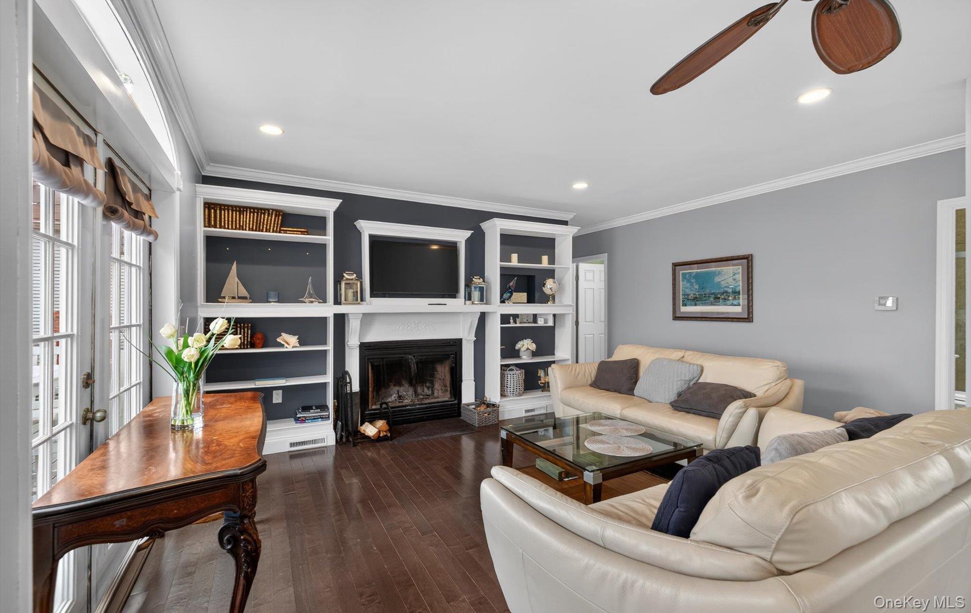 108 Awixa Avenue Bay Shore, NY 11706 - Photo 6 of 47 Living area with a ceiling fan, a glass covered fireplace, ornamental molding, dark wood finished floors, and built in features