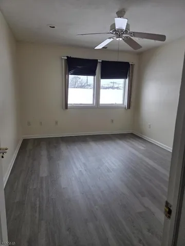 an empty room with wooden floor chandelier fan and windows