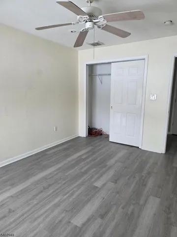 an empty room with wooden floor closet and fan
