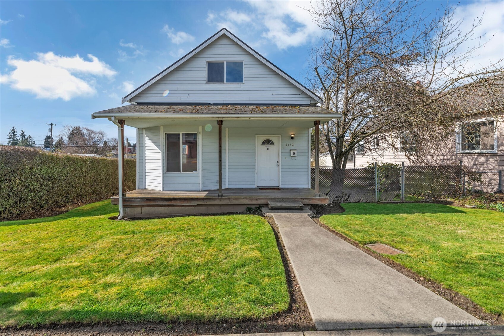a view of a white house with a yard potted plants and a large tree