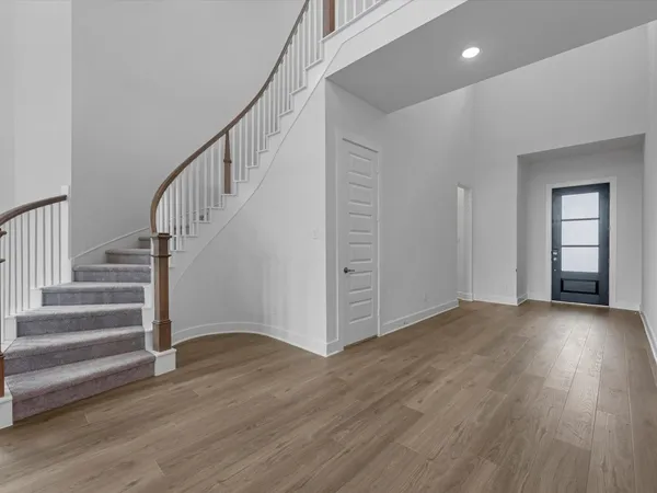 a view of an empty room with wooden floor and stairs