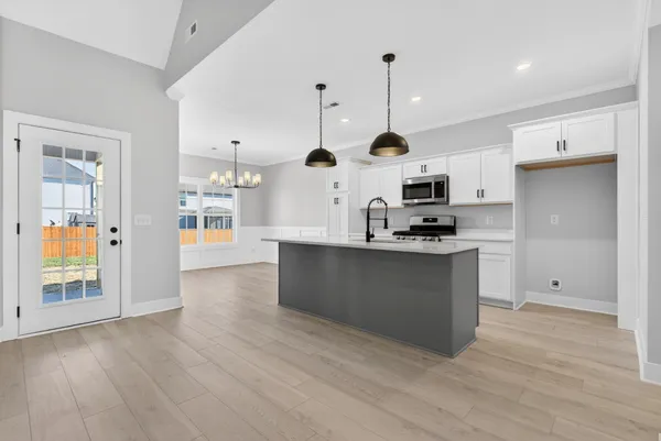 a kitchen with stainless steel appliances granite countertop a sink a microwave a stove and a wooden floors