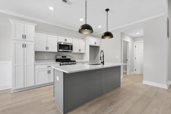 a large kitchen with stainless steel appliances a large counter top a stove a sink and a wooden floor