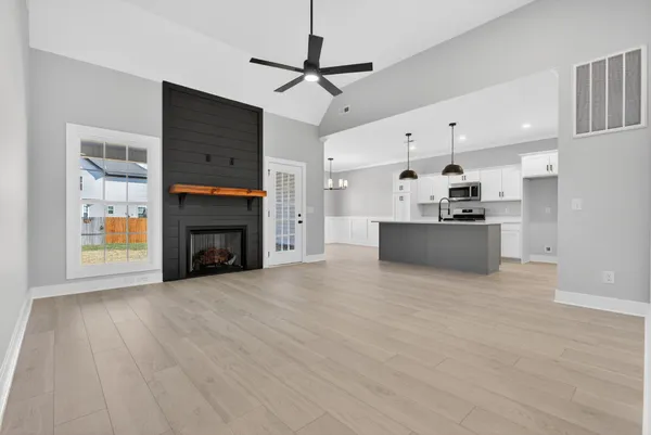 a view of an empty room with wooden floor fireplace and a window