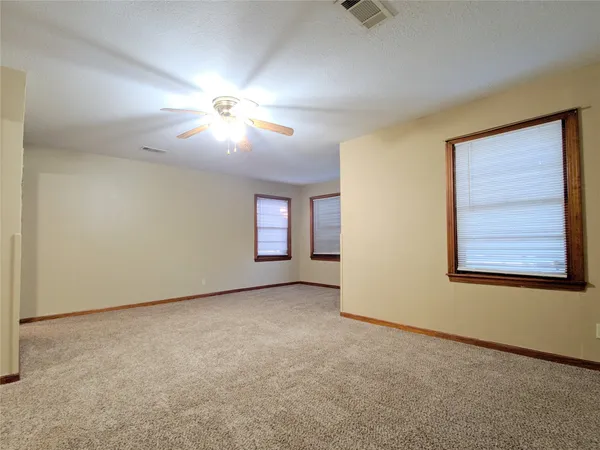 an empty room with windows and fan