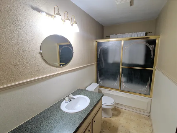 a bathroom with a granite countertop sink a toilet and a mirror