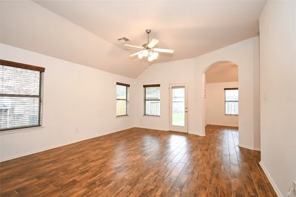a view of an empty room with a window and wooden floor