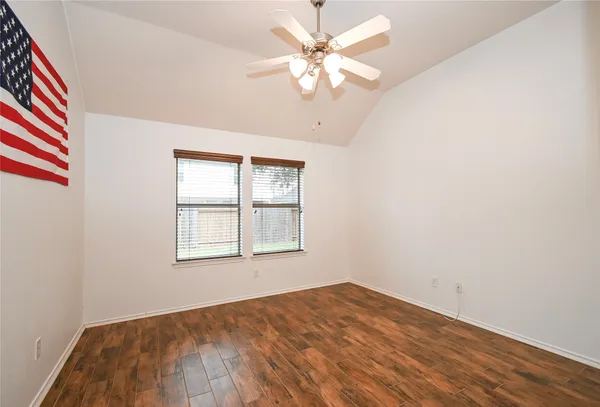 an empty room with chandelier fan and windows