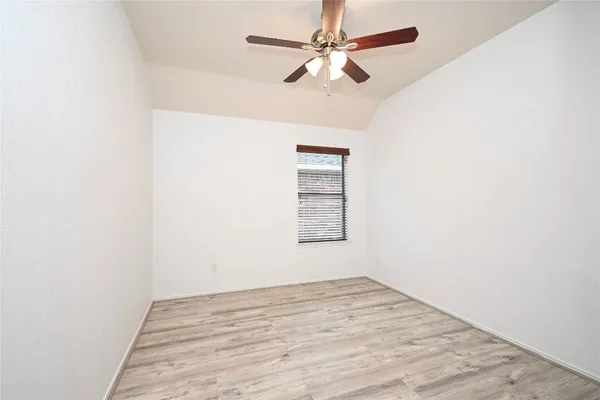 an empty room with a ceiling fan and wooden floor