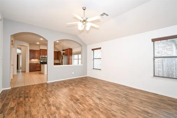 a view of an empty room with wooden floor and a window