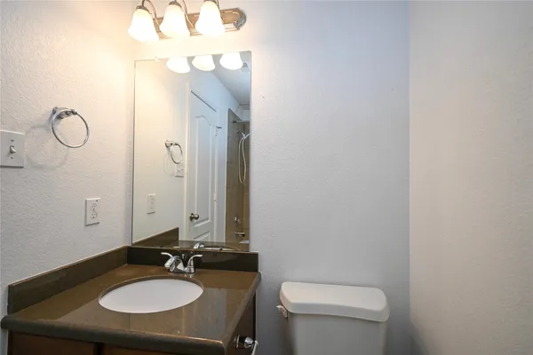 a bathroom with a granite countertop sink toilet and a mirror
