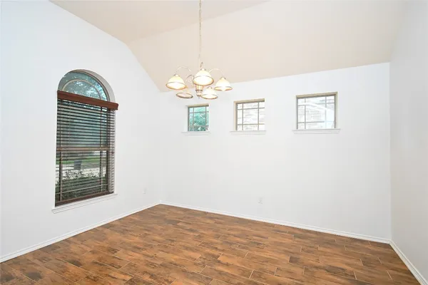 an empty room with wooden floor chandelier and window