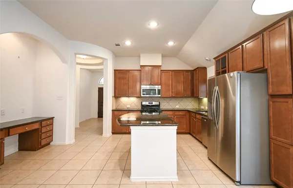 a kitchen with granite countertop a refrigerator and a stove top oven