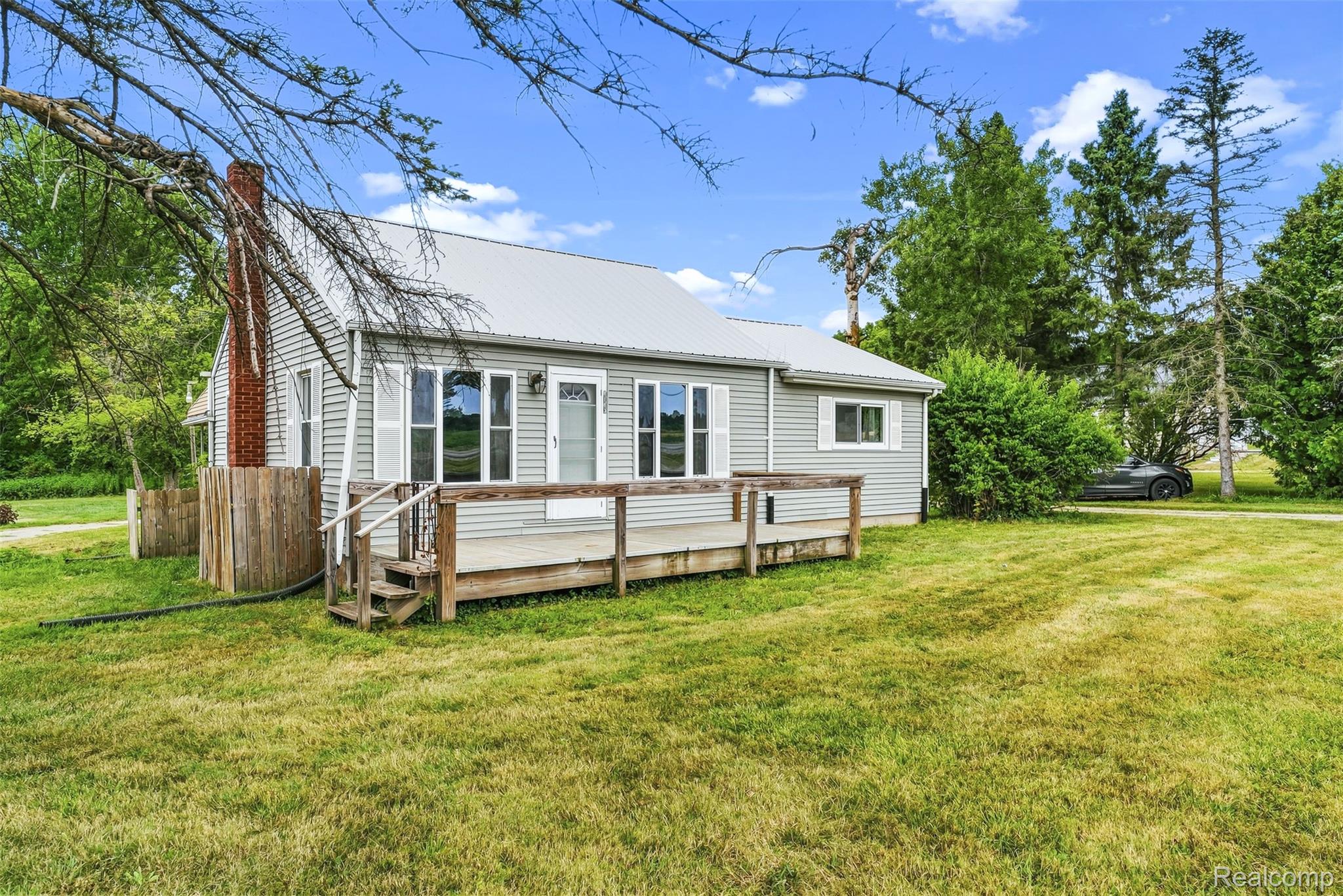 6163 North State Road Davison, MI 48423 - Photo 11 of 45 Siding exterior with a metal roof, front porch with wood decking, and a brick chimney