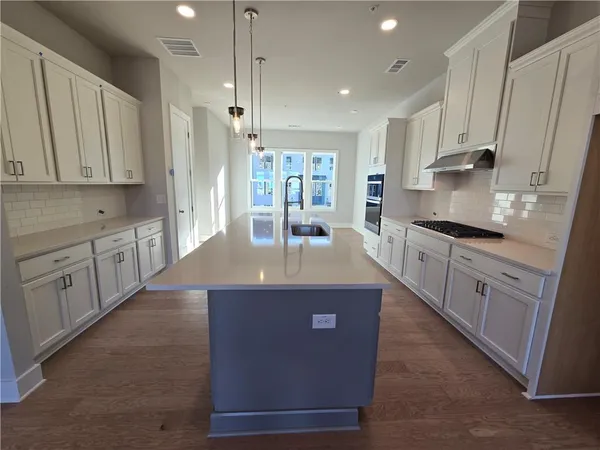 a kitchen with kitchen island granite countertop a sink a counter top space stainless steel appliances and cabinets