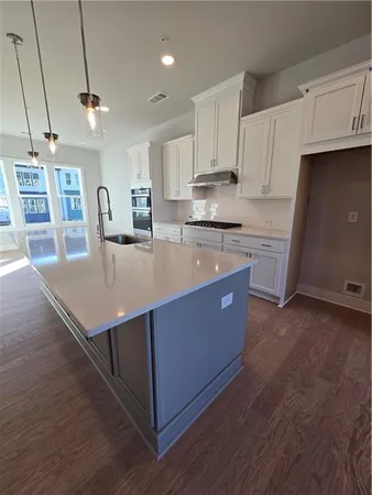 a kitchen with stainless steel appliances granite countertop a stove a refrigerator a sink dishwasher and white cabinets with wooden floor