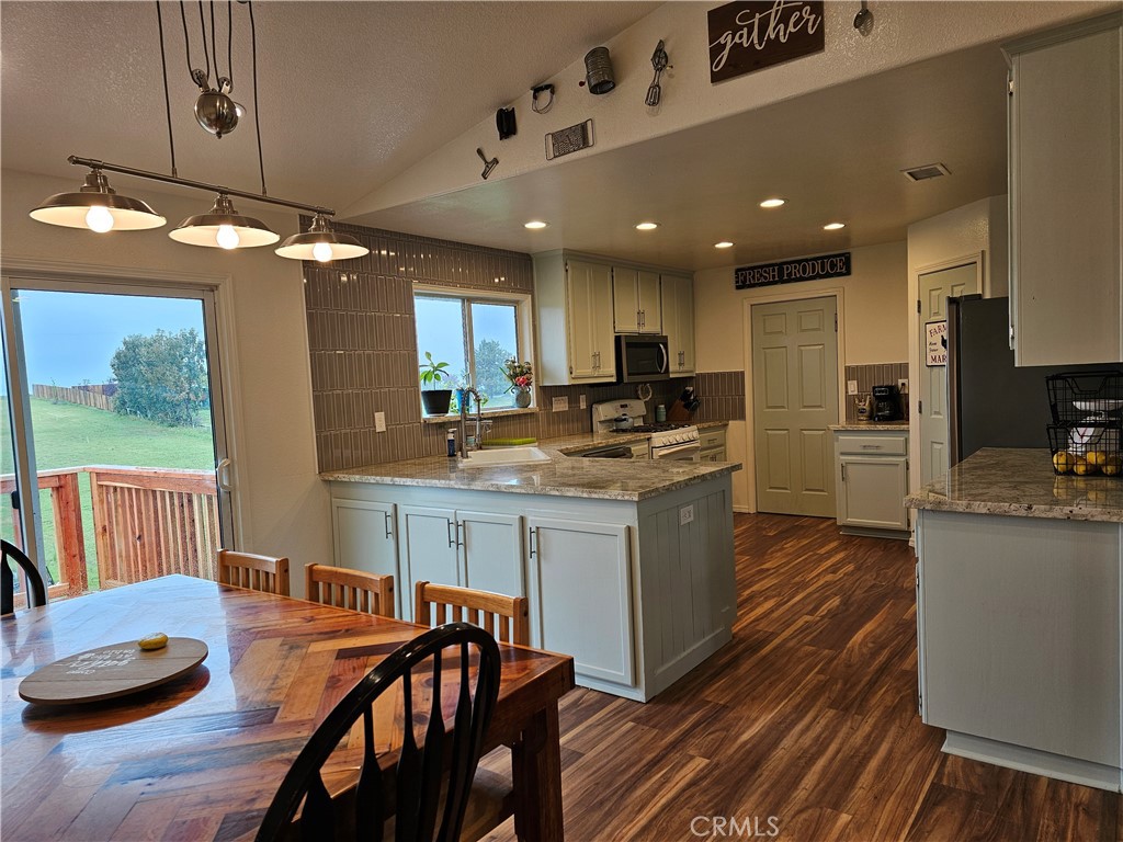 8199 Plane View Place Paso Robles, CA 93446 - Photo 4 of 22 a kitchen with stainless steel appliances granite countertop a stove refrigerator a sink dishwasher and a dining table with wooden floor