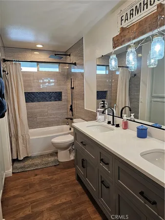 a bathroom with a double vanity sink toilet mirror and shower