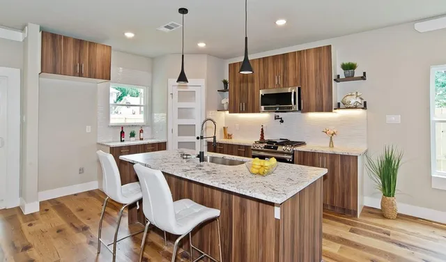 a kitchen with a refrigerator a stove a sink and a dining table with wooden floor