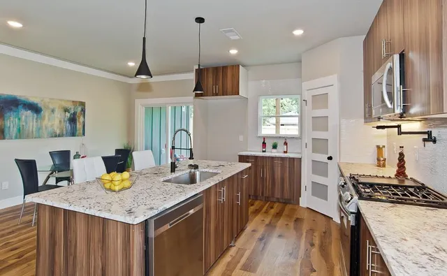 a kitchen with granite countertop a stove a sink a dining table and chairs