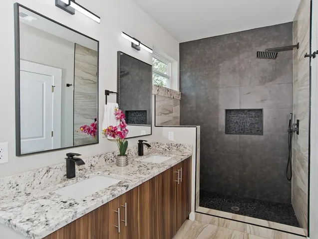 a bathroom with a granite countertop sink a mirror and shower
