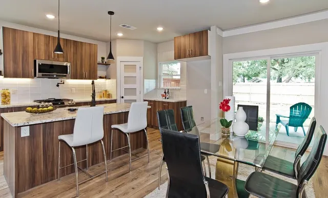 a kitchen with granite countertop stainless steel appliances a dining table and chairs
