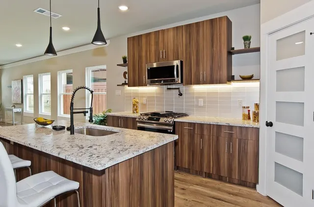 a kitchen with granite countertop stainless steel appliances a stove a sink cabinets and wooden floor