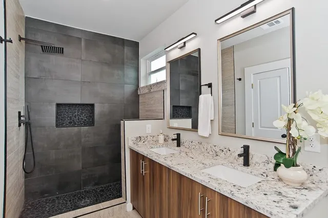 a bathroom with a granite countertop sink a mirror and shower