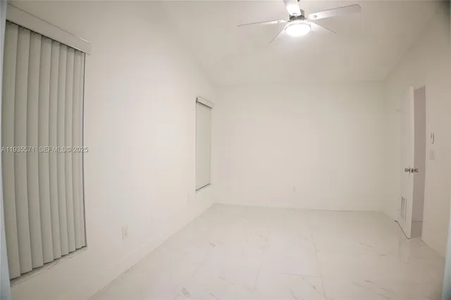an empty room with a ceiling fan and window