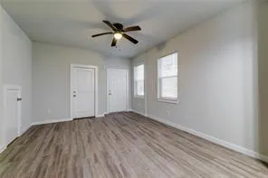 a view of empty room with wooden floor and fan